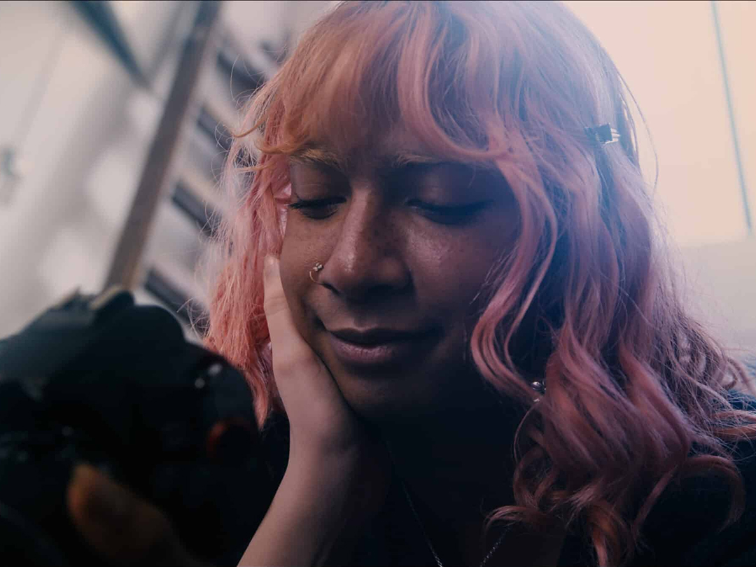 A pink-haired woman resting her face in her hand, from Terratoma.